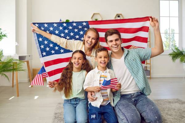 Happy, cheerful American patriot family. Portrait of a joyful young mother, father, and little children sitting on the floor at home
